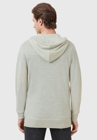 Maglione con cappuccio verde chiaro, dal taglio relaxed, maniche lunghe e tessuto strutturato. Le finiture a costine sui polsini e sull'orlo accentuano il design.