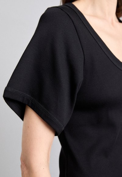Schwarzes geripptes T-Shirt mit tiefem V-Ausschnitt, kurzen Ärmeln und genähten Details. Der Stoff wirkt weich und strukturiert.