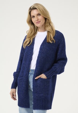 Tummansininen neulecardigan, jossa on pitkä avoin etuosa, ribbauskahvat ja kaksi etutaskua. Pehmeä rakenne ja löysä istuvuus.
