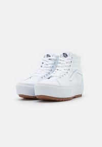 Zapatillas altas blancas con parte superior de lona texturizada, suela de plataforma y suela de goma. Presentan un cuello acolchado y un parche de logo.