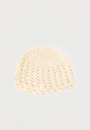 Cremefarbene, gehäkelte Mütze mit Lochmuster und kleinen dekorativen Perlen entlang des unteren Randes auf weißem Hintergrund.