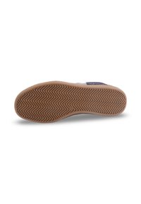 Chaussure à semelle en caoutchouc avec un motif en chevrons, dotée d'un dessus doux et de coutures contrastées. Le fond présente une adhérence texturée et multidirectionnelle.