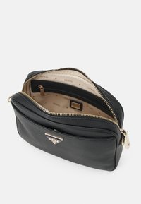 Czarna, skórzana torba na ramię z fakturowaną powierzchnią, złotym suwakiem i logo. Wnętrze wyścielone jasną, markową podszewką z kieszonką.