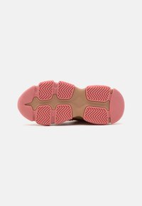 Semelle de chaussure avec un fond en caoutchouc rose et un motif zigzag texturé, présentant une semelle intermédiaire beige, mettant en avant un design ergonomique distinct.