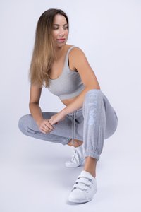 Light grey ribbed crop top and matching jogger pants with elastic cuffs, featuring a printed design on one leg, paired with white sneakers.