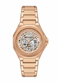 Reloj automático de oro rosa con un dial esqueleto transparente, acentos de diamantes, bisel octagonal y pulsera de metal enlazada.