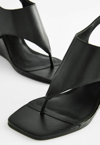 Sorte læder wedge-sandaler med et delt design, firkantet tå og diskrete syninger. Glat tekstur og minimalistisk stil.
