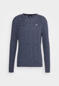 Pull en tricot bleu foncé avec un motif en câble, encolure ronde et manches longues. Comprend un petit logo sur la poitrine. Tissu texturé.