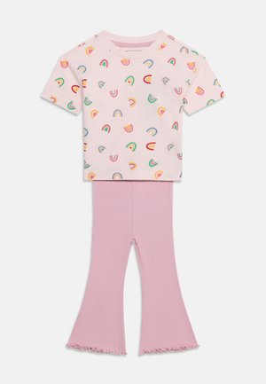 Detský dvojdielny outfit s ružovým tričkom s krátkym rukávom zdobeným farebnými dúhami a svetloružovými zvonovými nohavicami so zúbkovanými lemami.
