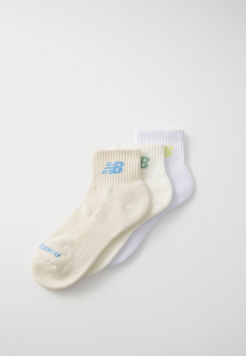 Tre par med ribbestrikkede sokker i beige, hvit og lysegrå, med kontrastlogoer i blått og grønt på ankelen.