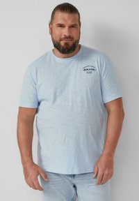 Lichtblauw T-shirt met korte mouwen en een gemêleerde textuur. Voorzien van een kleine donkere print op de linkerkant van de borst. Casual pasvorm, ronde halslijn.