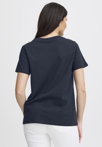 Tmavě modré bavlněné tričko s krátkými rukávy a kulatým výstřihem, s hladkou strukturou a pohodlným střihem. Zobrazen pohled zezadu.