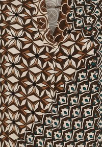 Mønstret stof har geometriske designs i brunt, creme og teal, med en blanding af stjerne- og diamanformer. V-halsudskæring øverst.