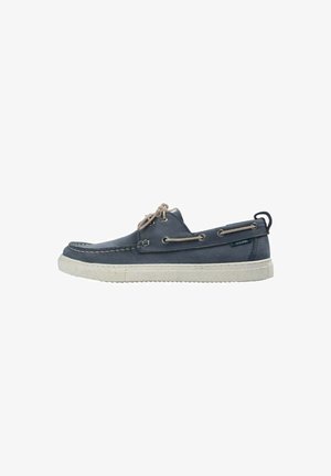 Zapato náutico de cuero azul marino con cordones beige, suela de goma blanca, ojales laterales y tira para tirar en el talón.