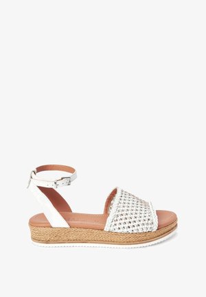 Sandales tissées blanches avec une tige tressée et une bride à la cheville, dotées d'une semelle épaisse en espadrille tissée et d'une semelle intérieure en cuir lisse.