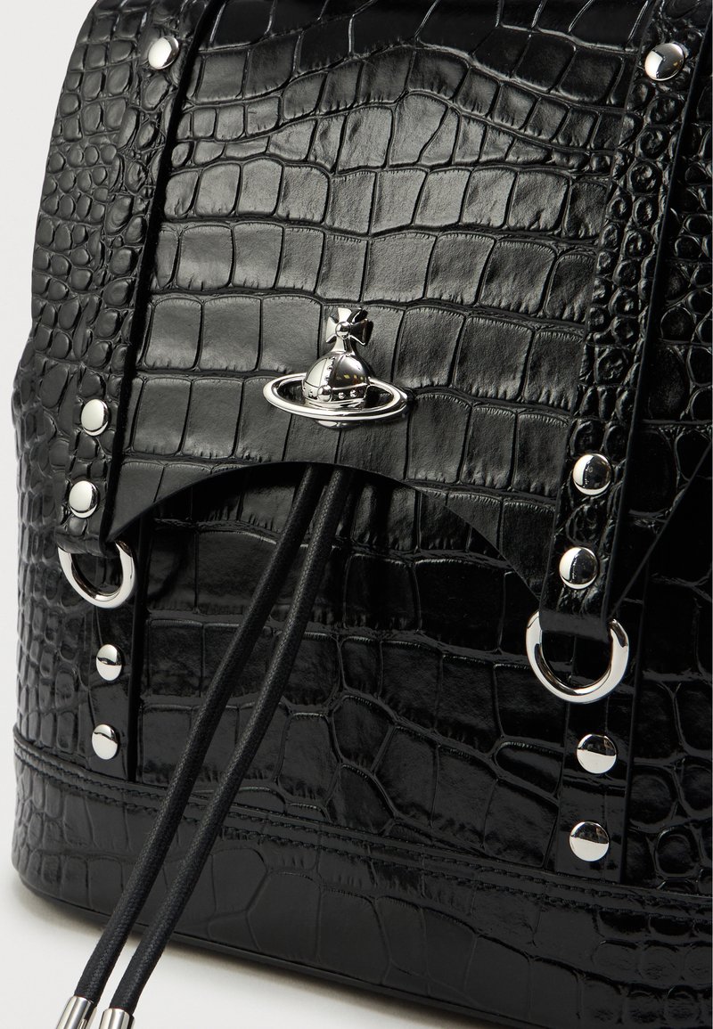 Zaino nero in pelle con stampa a coccodrillo, con accenti metallici, dotato di chiusura a coulisse, hardware decorativo a forma di pianeta e anelli metallici circolari.