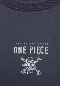 Námornícky modré bavlnené tričko s bielym textom "PÁN OCEÁNU" a "ONE PIECE" nad grafikou lebky a skrížených kostí s klobúkom.