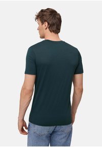 Türkises T-Shirt mit kurzen Ärmeln aus Baumwollmischung, mit Rundhalsausschnitt und geradem Saum. Getragen mit hellblauen Jeans.