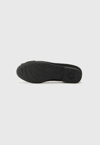 Black rubber shoe sole featuring textured grip patterns and a curved shape. Logo embossed on the side. Smooth edges with no visible wear.