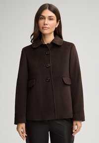 Cappotto di lana marrone con colletto, quattro bottoni e due pattine per le tasche. Presenta una forma dritta e una texture liscia. Design semplice.