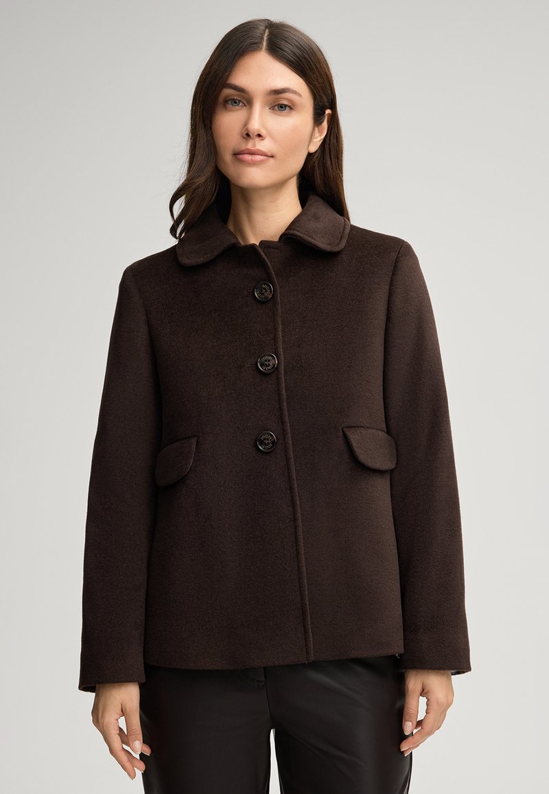 Cappotto di lana marrone con colletto, quattro bottoni e due pattine per le tasche. Presenta una forma dritta e una texture liscia. Design semplice.