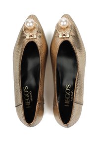 Złote metaliczne buty z szpiczastym noskiem, o teksturowanej powierzchni, z perłowym akcentem i okrągłym okuciem na wierzchu. Czarna podszewka wewnętrzna.