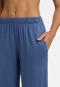 Modré, lehké, elastické kalhoty s gumovým pasem, bočními kapsami a hladkým povrchem. Ideální pro volnočasové nebo aktivní nošení.