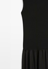 Czarna sukienka bez rękawów z prążkowanym dzianinowym gorsetem i marszczonym, zwiewnym dołem na białym tle.