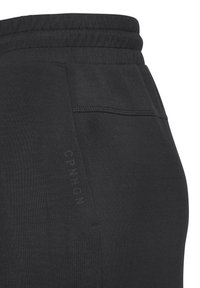 Melnas sporta bikses ar elastīgu jostu, sānu kabatām, izšuvuma detaļām un drukātu logo uz kabatas. Gluda auduma tekstūra.