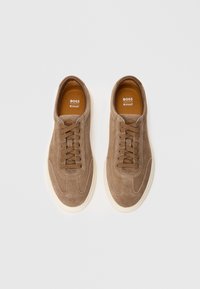 Pair of brown suede Boss sneakers with brown laces and white soles, viewed from above on a white background.