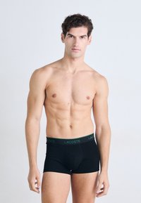 Zwarte boxershorts van katoen met een groen Lacoste-logo op de tailleband. Het ontwerp heeft een strakke pasvorm en een middelhoge snit.