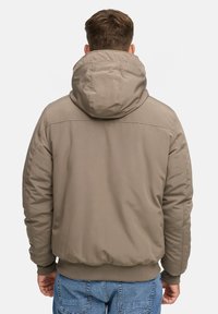 Khaki pufjakke med hætte, der har en glat struktur, ribbet kant og manchetter samt syet detaljer på skuldrene.
