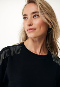 Schwarzer Sweatshirt mit metallischen Perlenverzierungen an den Schultern, geripptem Rundhalsausschnitt und weichem Material, das ein lässiges und zugleich elegantes Design hervorhebt.