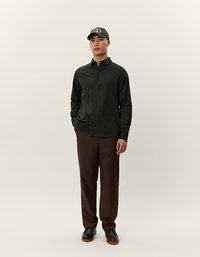 Temno zeleni stripek srajca s gumbi, rjave hlače, temni čevlji in temno zeleni klobuk. Gladko blago s klasičnim krojem in zapiranjem na gumb.
