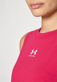 Top ajustado y sin mangas de color rosa, hecho de una tela suave, con un logo blanco en el pecho. Textura suave, escote redondo clásico.