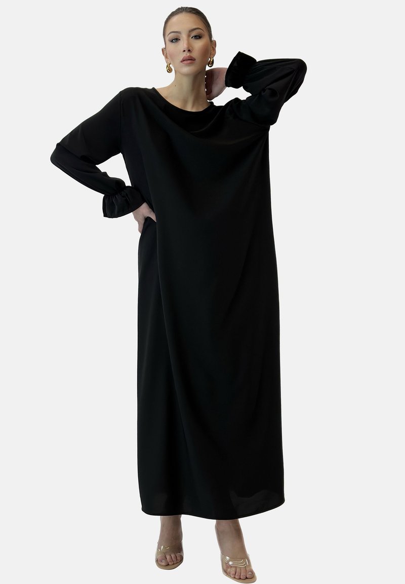 Schwarzes, langärmliges Kleid mit lockerem Schnitt, das geraffte Bündchen und einen Bootsausschnitt hat; aus glattem Stoff gefertigt und knöchellang.