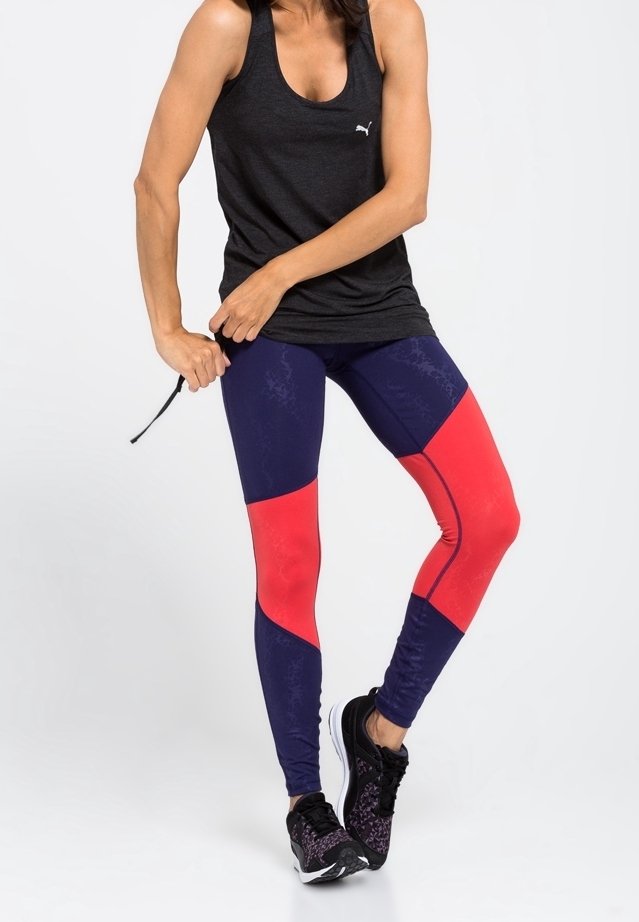 Svart linne, marinblå och röda leggings med färgblockering och texturerade paneler, i kombination med svarta sportskor. Texturerade tyger.