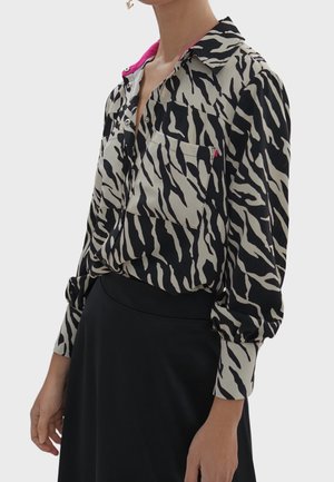 Langarmshirt met een zwart en beige zebrapatroon, met een roze kraag, knoopsluiting aan de voorkant en twee borstzakken. Zachte stof, ontspannen pasvorm.