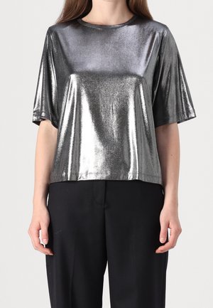 Metallisch zilveren t-shirt met korte mouwen, een ronde halslijn en een relaxed fit. De stof heeft een glanzende afwerking, die contrasteert met zwarte broeken.
