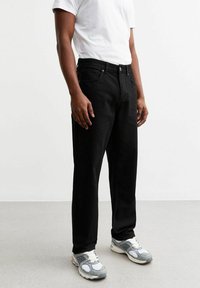 Jeans in denim nero con vestibilità dritta, presentano un bottone e una cerniera, design a cinque tasche e dettagli di cucitura sottili.