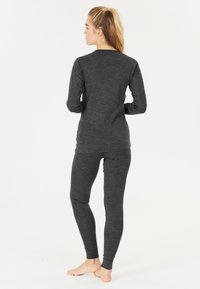 Graues langärmliges Oberteil und passende, schmal geschnittene Hose aus weichem, strukturiertem Stoff. Das Outfit hat einen Rundhalsausschnitt und schmal zulaufende Bündchen.