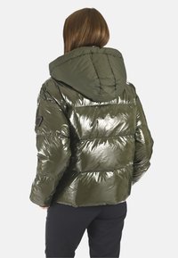 Doudoune olive avec une texture matelassée brillante, dotée d'une capuche et d'un patch logo sur l'épaule gauche.