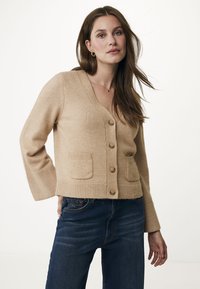 Beige ullkofta med V-ringning, framknappar, ribbade ärmslut och två framfickor, med en mjuk textur och avslappnad passform.