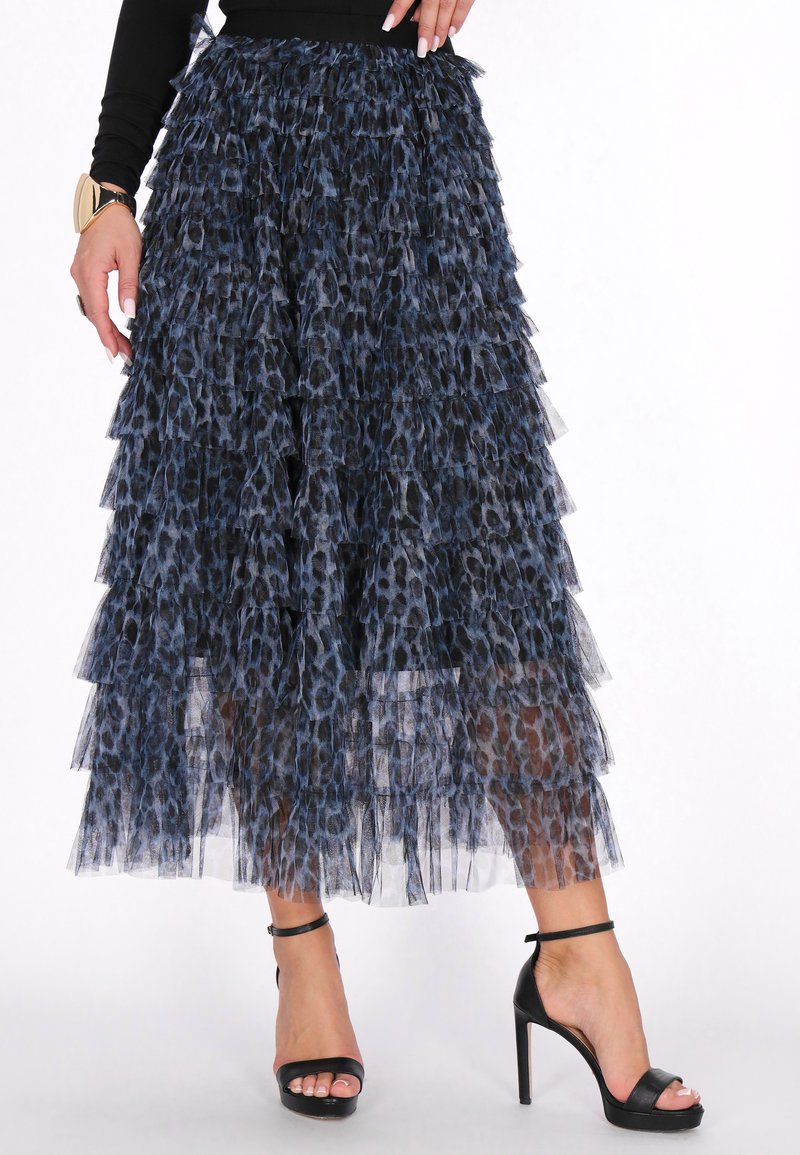 Két rétegű tüll szoknya kék és fekete leopárdmintával, réteges fodrokkal és áttetsző textúrával, fekete pántos magassarkú cipővel párosítva.