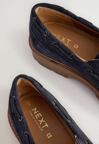 Pantofi slip-on din suede bleumarin, cu interior din piele bej, detalii cusute și grommete metalice. Inscripția „NEXT Forever Comfort” embosată pe branț.