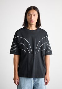 Black cotton t-shirt with white striped accents on sleeves and a curved chest design. Crew neckline. Relaxed fit, solid texture.