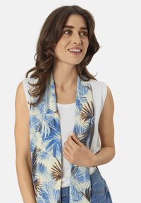 Lightweight scarf featuring a cream background with blue and brown tropical palm leaf patterns. Soft texture, long rectangular shape.
