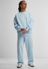 Hellblaues Sweatshirt und passende Hose aus weichem Stoff, mit geripptem Saum und Bündchen, sowie dezentem Logo-Detail auf der Brust.