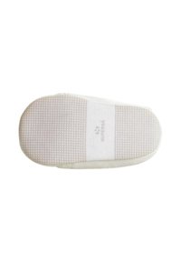 Suola di sneaker bianca con grip in gomma testurizzata, caratterizzata da una superficie liscia e un logo stampato in colore contrastante. Forma leggermente arrotondata.