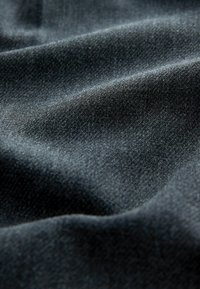 Mørkegråt stof med en blød, struktureret overflade, der viser subtile bølger og variationer i tone, hvilket indikerer et tungt, holdbart materiale.